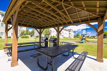 A wooden pavilion with a black table and benches.